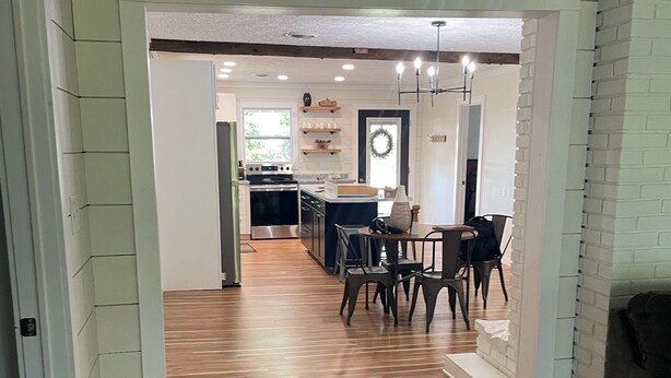 A modern kitchen with a central island, wooden flooring, and a dining area with chairs and a table. - Oxbow Overlook: Ohio River Bend Views, Private Pond, Pets Welcome (Magnet)