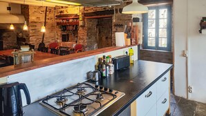 Une cuisine rustique avec un cuisinière à gaz, un comptoir en bois et des murs en pierre.