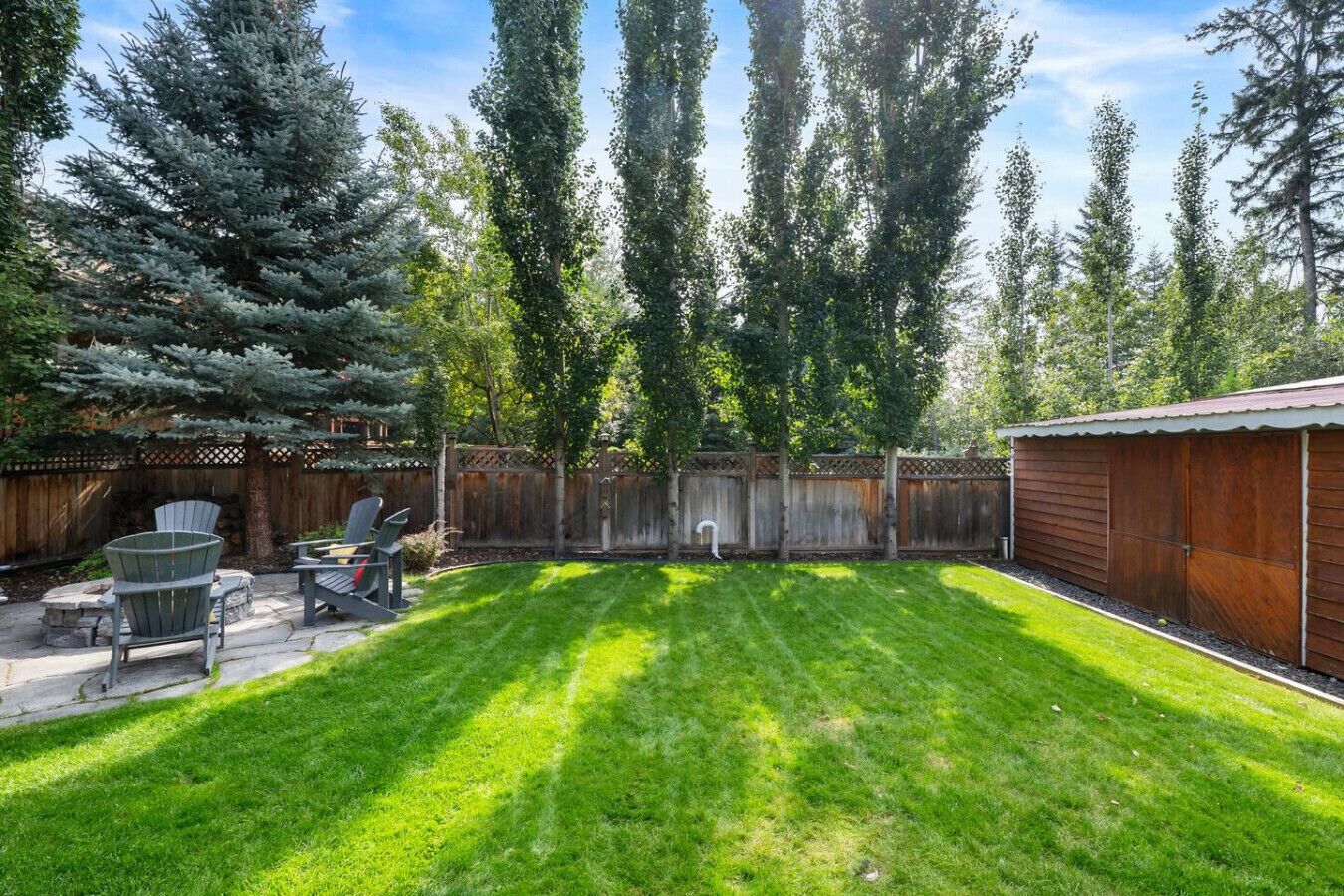 A backyard with a wooden deck, a barbecue area, and a fenced yard.
