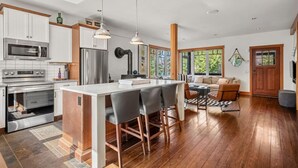 A modern kitchen with stainless steel appliances, a central island, and a dining area with a sofa and chairs.