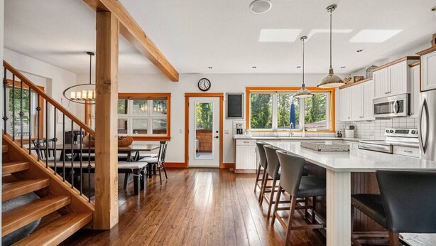 A modern kitchen with wooden floors, white cabinets, and a large island.