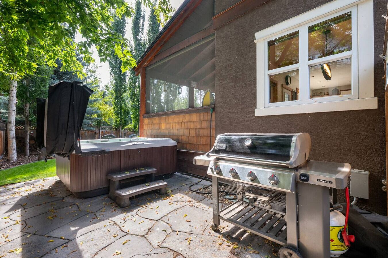 Un jardin avec un jacuzzi, un barbecue et un espace patio couvert.