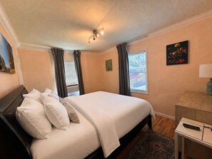 A hotel room with a bed, a desk, a lamp, a painting, and a window with curtains. - Posh 4BD3BA - 2 Living Rooms - Gameroom - Patio - BART - Walk to Grocery (Concord)