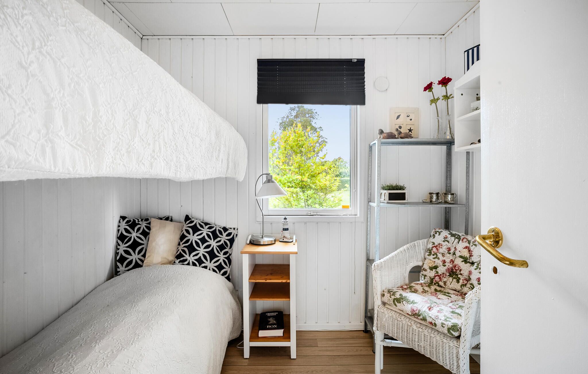 Ein Schlafzimmer mit Etagenbett, Schreibtisch mit Lampe, Stuhl und Fenster mit Blick auf Bäume.