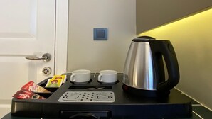 A coffee machine with two cups, a kettle, and a coffee pod holder with Nescafe and Dolce Gusto pods. - Emily Taksim Hotel (İstanbul)