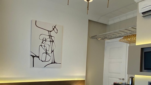 A hotel room with a bed, bedside lamps, a wall-mounted abstract artwork, a wardrobe, and a television. - Emily Taksim Hotel (İstanbul)