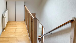 Un escalier en bois avec une rampe métallique menant à un palier.