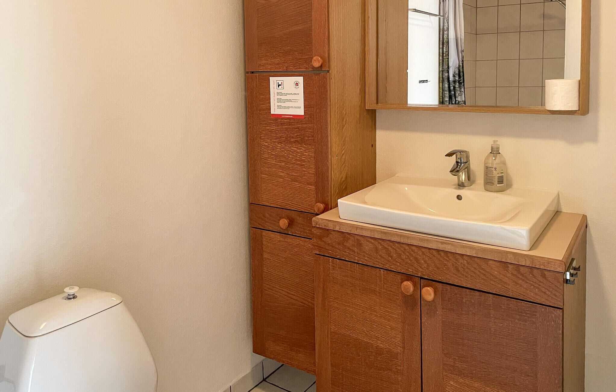 A bathroom with a white sink, a mirror, and wooden cabinets.