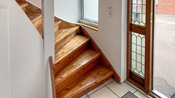 Un escalier en bois menant à une porte surmontée d’un portail en métal.