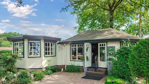 Une maison à deux étages, avec un chemin de briques menant à l’entrée, entourée d’une végétation luxuriante.