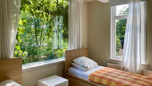 A bedroom with a wooden bed, a bedside table, and a window with a view of greenery. - Amazing home in Stolwijk with house sea view (Stolwijk)