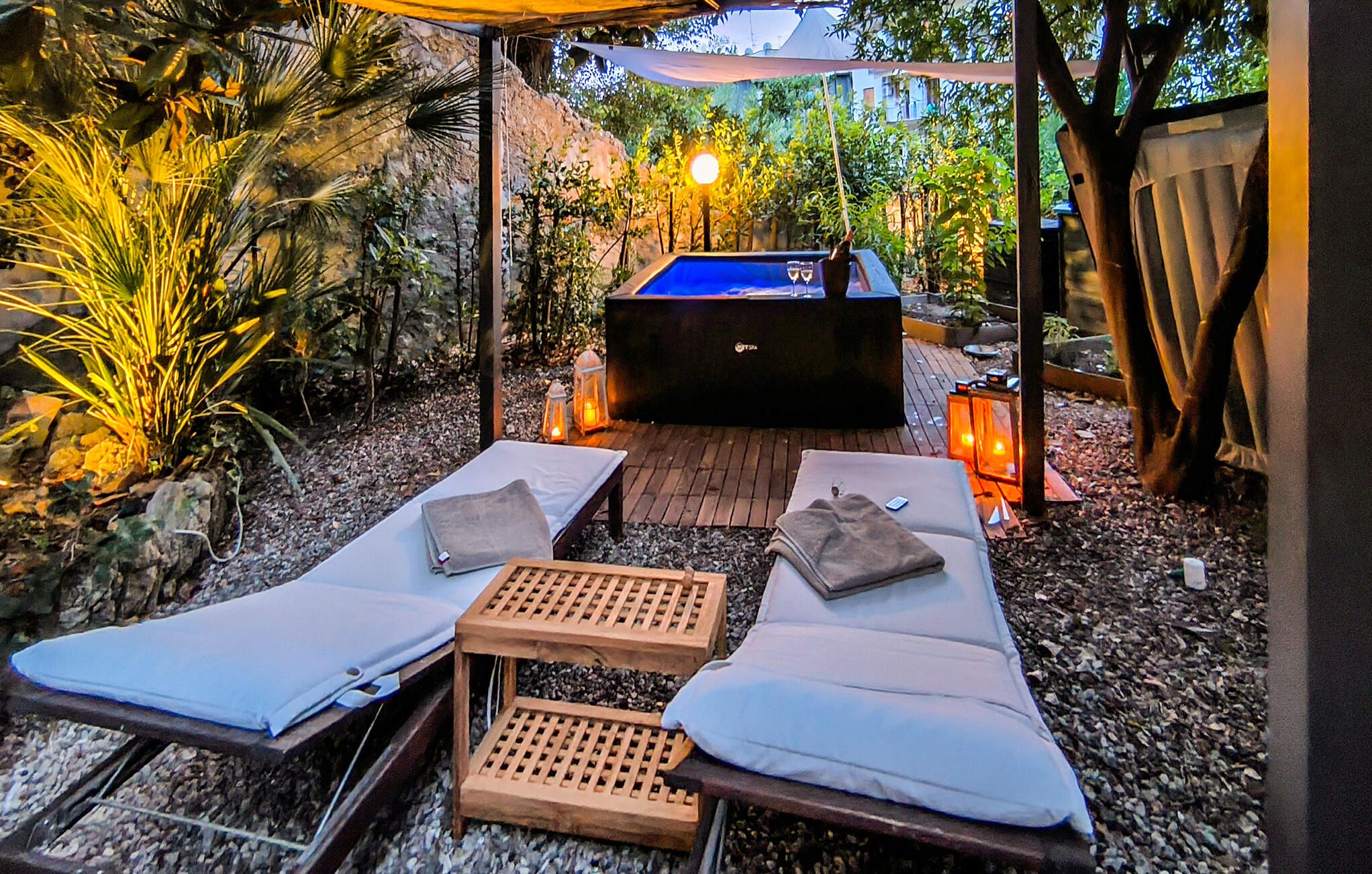 Een wellnessruimte met twee ligstoelen, een klein houten tafeltje en een jacuzzi.