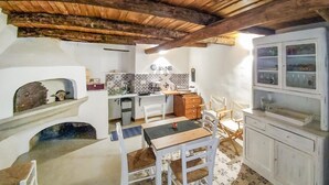 A compact kitchen with a tiled backsplash, wooden cabinets, and a dining area with a table and chairs. - 2 bedroom beautiful home in Cava de' Tirreni (Cava de' Tirreni)