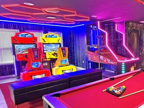 A pool table with a billiard cue and balls, a neon-lit arcade with racing game machines, and a basketball court with a scoreboard.