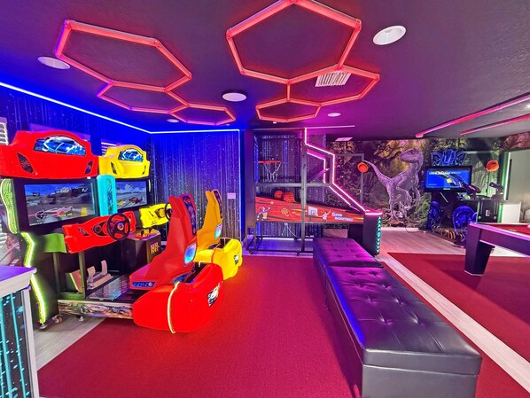 A gaming arcade with neon lights, racing simulators, and a basketball court.