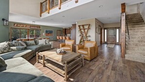 A spacious living area with a high ceiling, wooden staircase, and a view of the outdoors. - The Deadwood Lookout-Sleeps 22 (Sturgis)