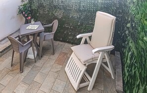 Un espace patio comprenant une table et deux chaises, un mur décoratif et une plante en pot.