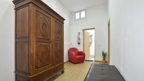 Un pasillo con un armario de madera, una silla roja y un banco.