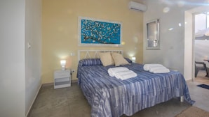 Une chambre à coucher avec un lit, deux tables de chevet, une commode, un tableau et une fenêtre.