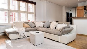 Una sala de estar moderna con un sofá modular, un reposapi és y un control remoto encima.