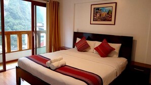 Een hotelkamer met een groot bed, een raam met uitzicht op groen en een schilderij aan de muur.