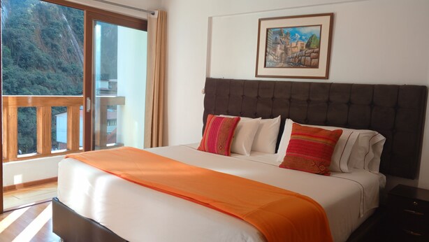 Een slaapkamer met een groot bed, een raam met uitzicht op een berg en een schilderij aan de muur.
