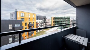 En balkong med utsikt över höga byggnader, inklusive en gul och grå byggnad samt en grön byggnad med balkonger.