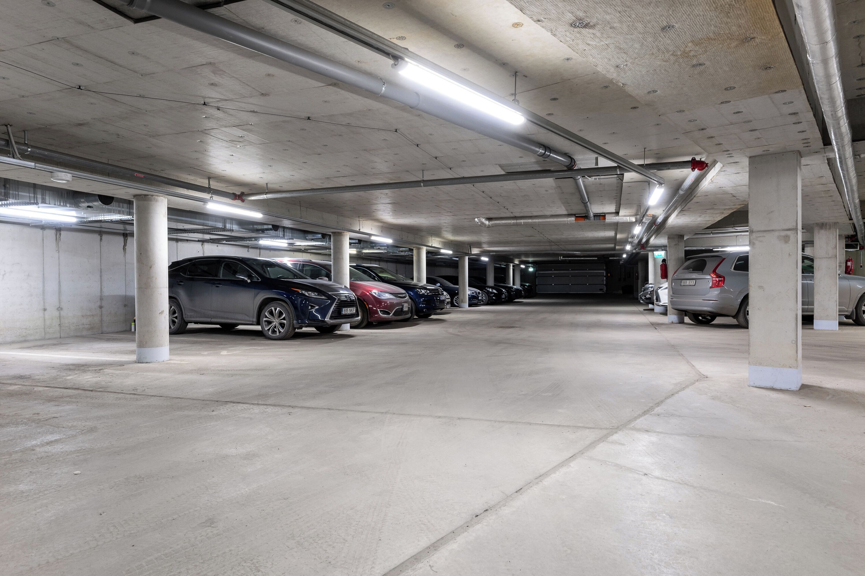 Un parking à plusieurs niveaux, doté de piliers en béton et d’un éclairage au plafond.