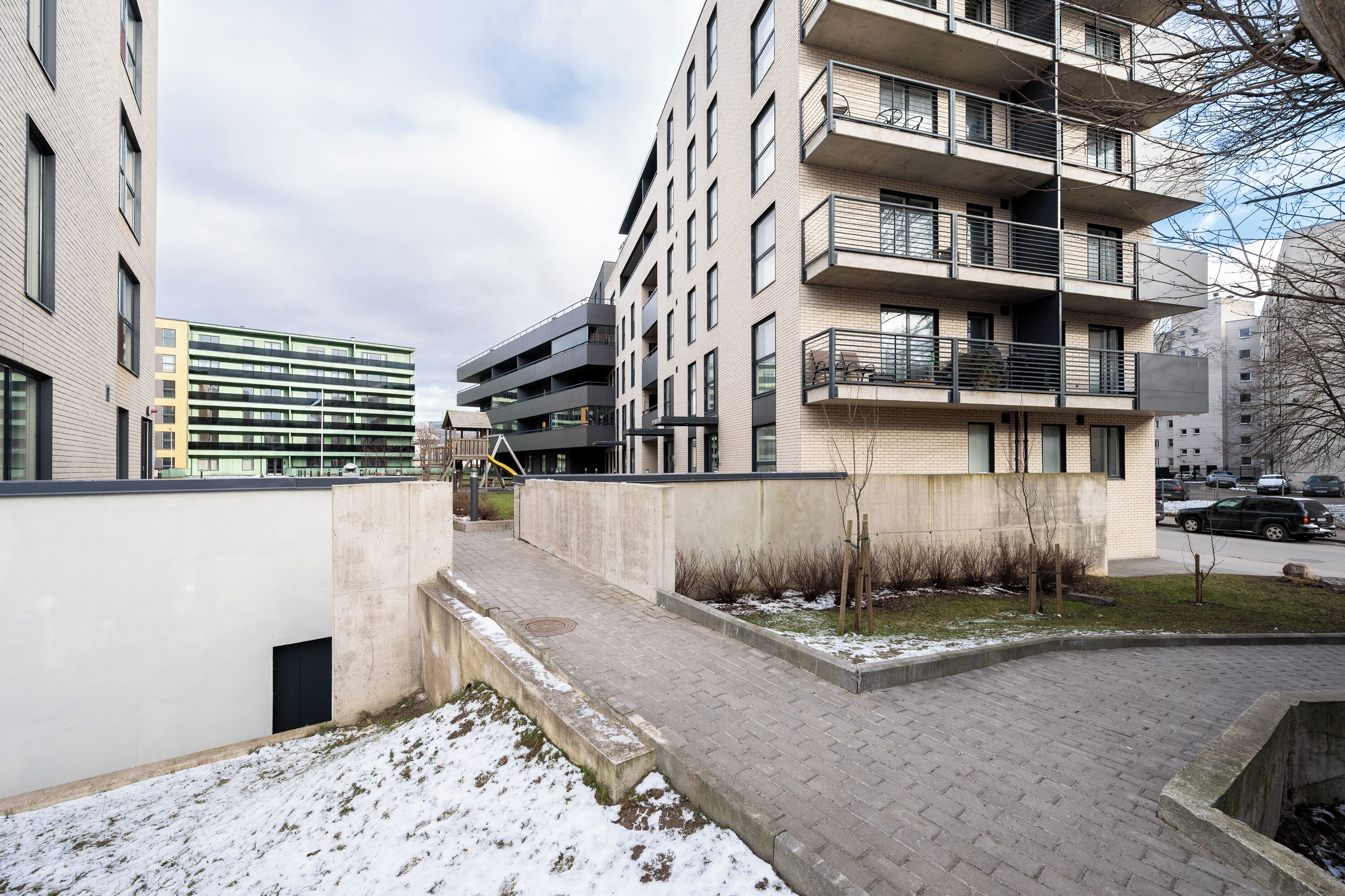 Ein modernes Mehrfamilienhaus mit mehreren Balkonen und einem gepflasterten Gehweg.