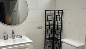 A bathroom with a white sink, mirror, toilet, and a black decorative partition.