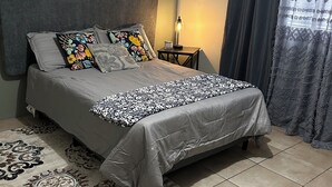 A bedroom with a bed, a nightstand, a lamp, and a patterned rug.