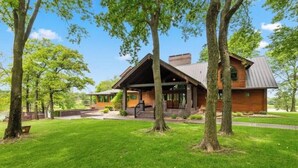 Et moderne hus med en overdækket veranda, omgivet af en velplejet græsplæne og træer.