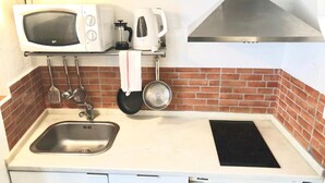 Une cuisine compacte équipée d’un four à micro-ondes, d’un grille-pain, d’une bouilloire et d’une cuisinière.