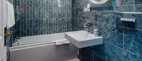 A modern bathroom with a bathtub, two sinks, and a toilet.