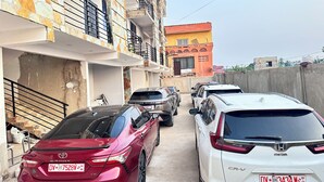 A row of parked cars along a residential street with multi-story buildings, some with balconies. - TN Residence  (Accra)