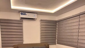 A bedroom with a bed, nightstands, an air conditioning unit, and a window with blinds. - TN Residence  (Accra)