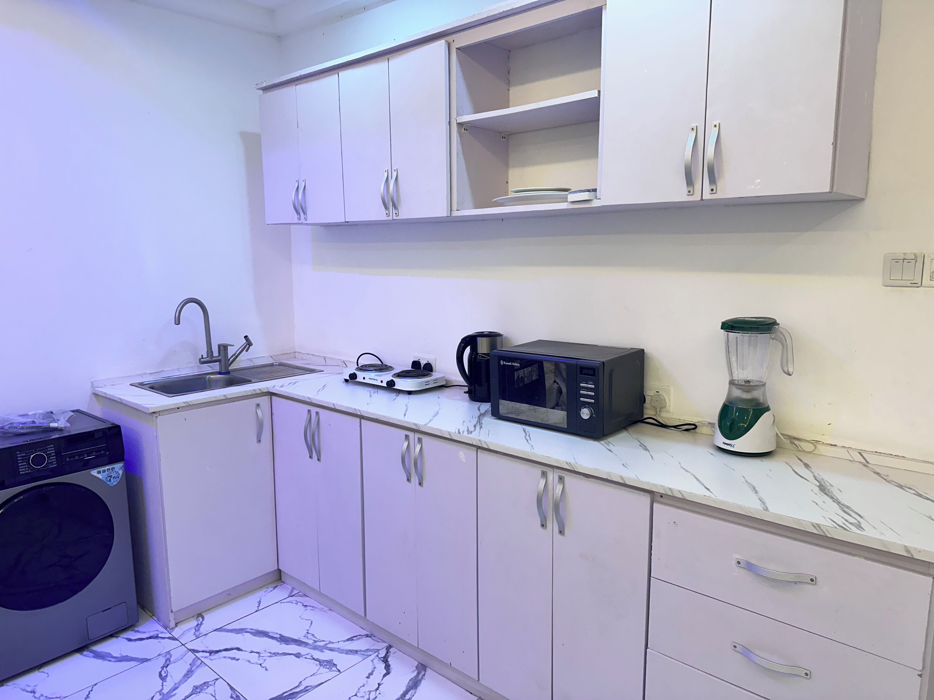 Cocina compacta con lavamanos, microondas, licuadora y lavadora.