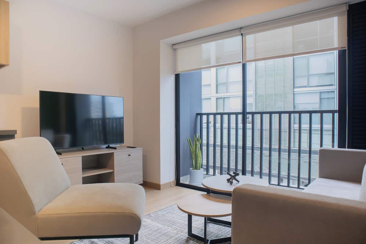 Uma sala de estar moderna com televisão de tela plana, sofá, mesa de centro e uma planta em vaso.