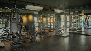 Une salle de sport moderne dotée de divers appareils d’exercice, de murs en verre et d’un intérieur propre et bien éclairé.