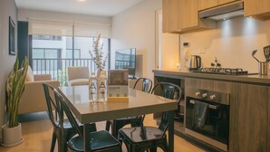 Une cuisine moderne avec des meubles en bois, un four encastré et un coin repas comprenant une table et des chaises.