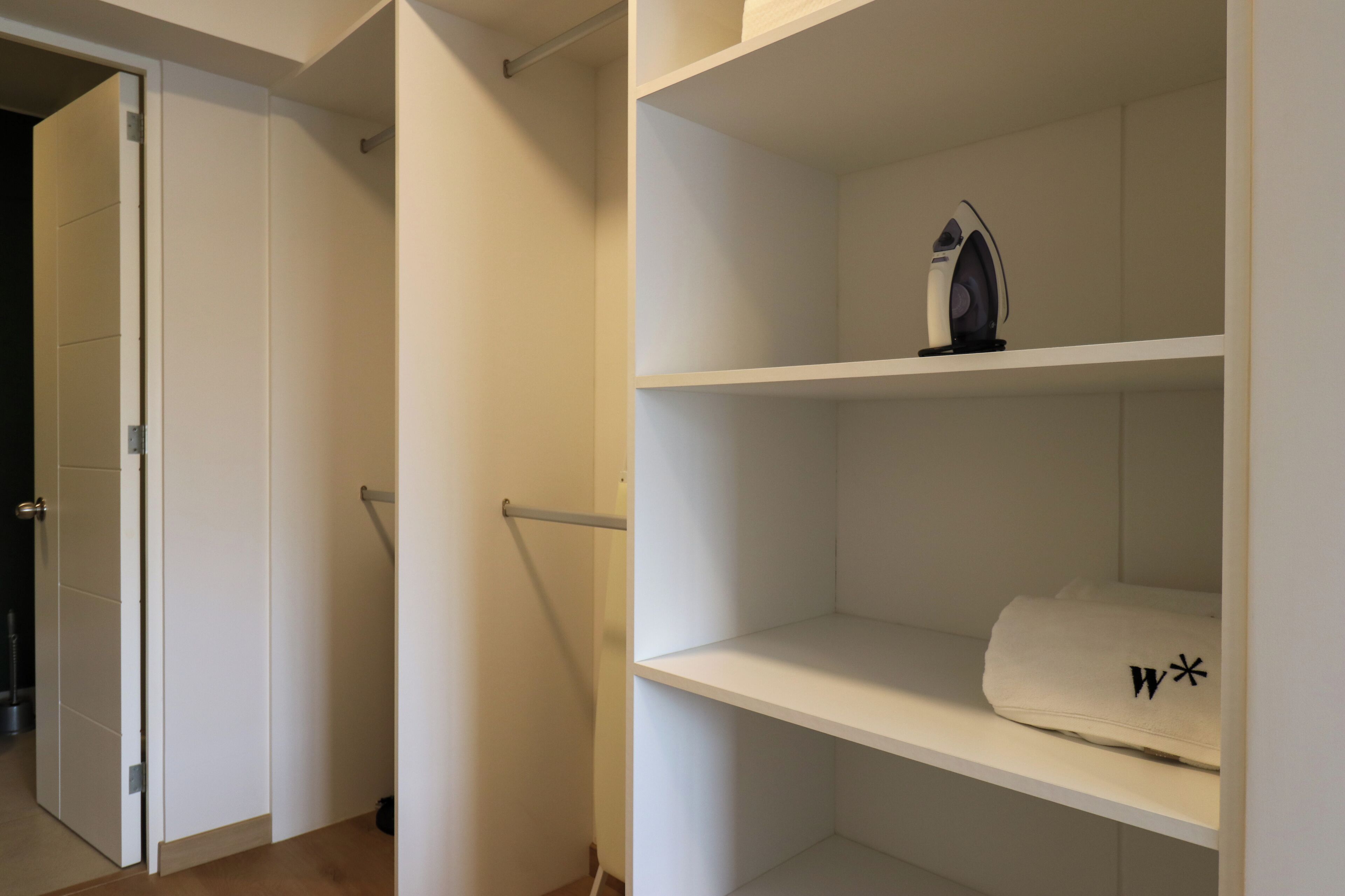 Ein weißer Schrank mit Regalen, einer Kleiderstange und einem Handtuch mit einem Logo.