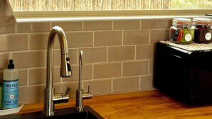 Uma cozinha com pia moderna, bancada de madeira e potes com condimentos.