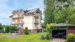 A multi-story residential building with balconies, a covered outdoor seating area, and a well-maintained lawn.