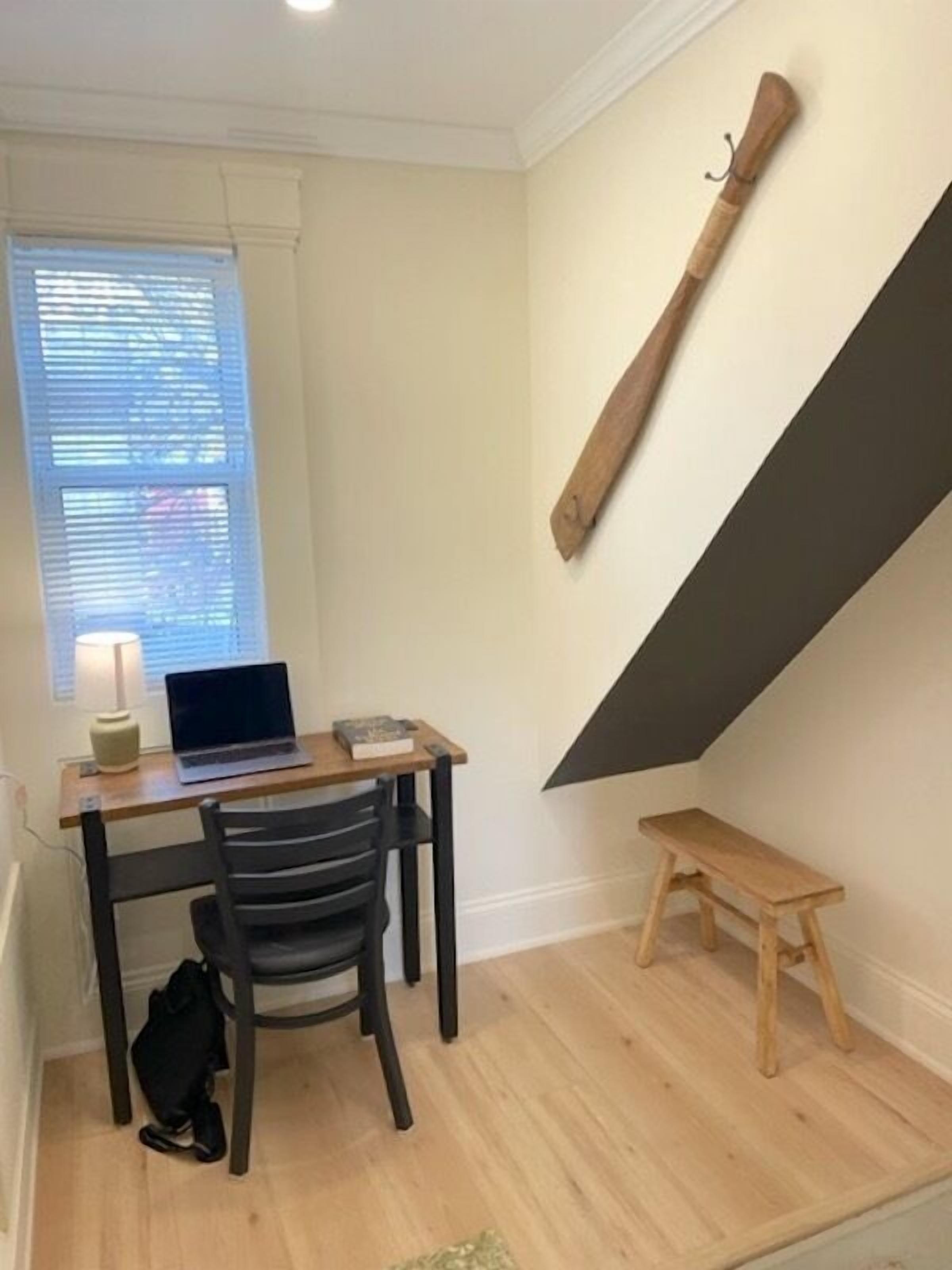 Une petite pièce comprenant un bureau, une chaise et un banc en bois.