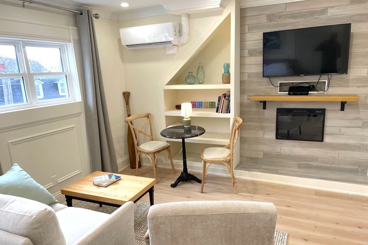 Una sala de estar con un sofá, dos sillones, una mesita, un televisor y una chimenea.