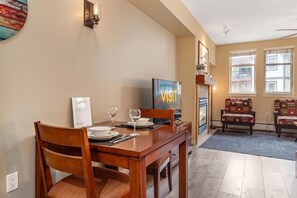 A dining area with a wooden table, chairs, a television, and a wall-mounted sign.
