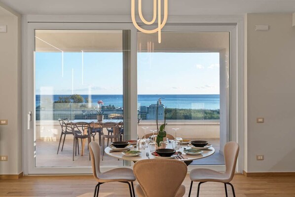 A dining area with a view of the sea, a balcony with outdoor seating, and a modern interior design. - Luxury Sea-View Penthouse - 4BR - Terrace - Arechi (Campania)