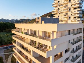 A multi-story residential building with balconies, a flat roof, and a view of the surrounding landscape. - Luxury Sea-View Penthouse - 4BR - Terrace - Arechi (Campania)