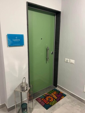 A green door with a handle, a small table with a clear glass top, a colorful rug, and a sign above the door. - Luxury Sea-View Penthouse - 4BR - Terrace - Arechi (Campania)