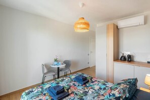 A hotel room with a bed, a small table with chairs, a hanging light fixture, and a built-in shelf with a coffee maker. - Luxury Sea-View Penthouse - 4BR - Terrace - Arechi (Campania)